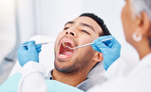 Patient receiving a professional dental exam with tools in a modern clinic.