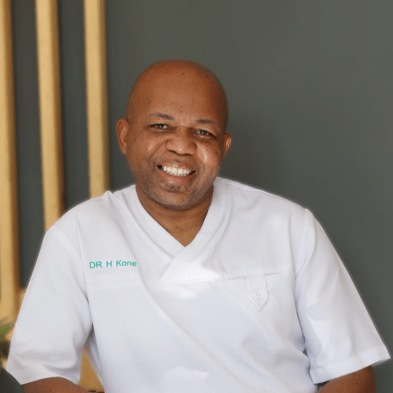 Dr. HN Kone, an experienced dentist with expertise in orthodontics, fast braces, and aligners, smiling confidently in a professional clinic setting.
